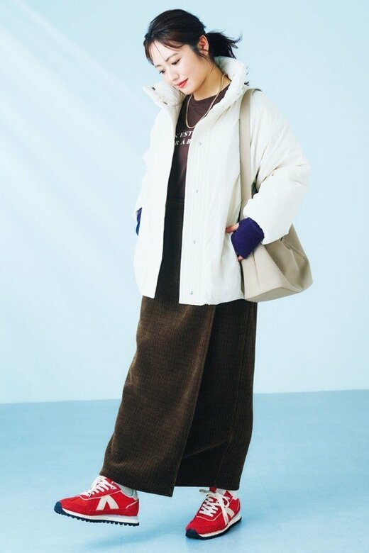 白いダウンを着て下を見る磯山さやかさん