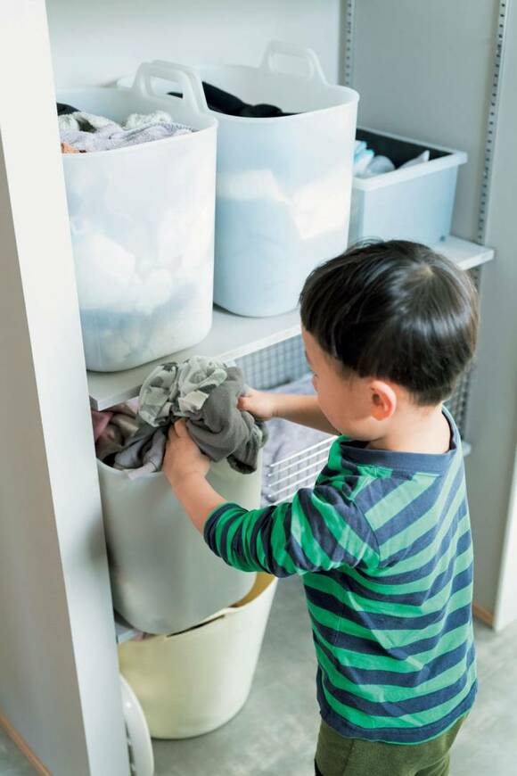 子どもが洗濯物をランドリーボックスに入れる様子