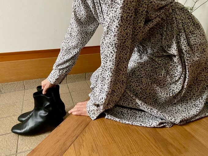 玄関にしゃがんで靴を持っている女性の姿
