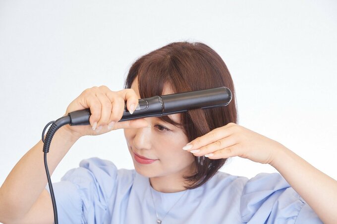 ヘアアイロンをする女性