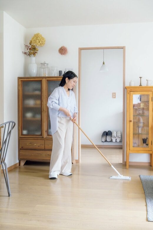 足つき家具の周りを女性が床掃除をする様子