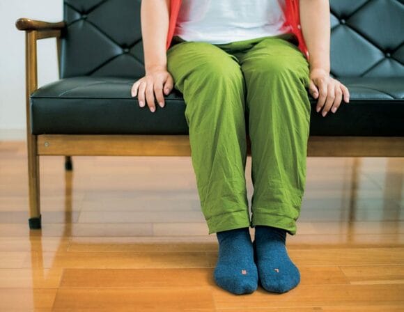 緑のパンツの人ソファに座る