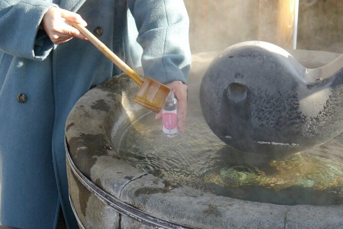 源泉のお湯をペットボトルにくむ様子
