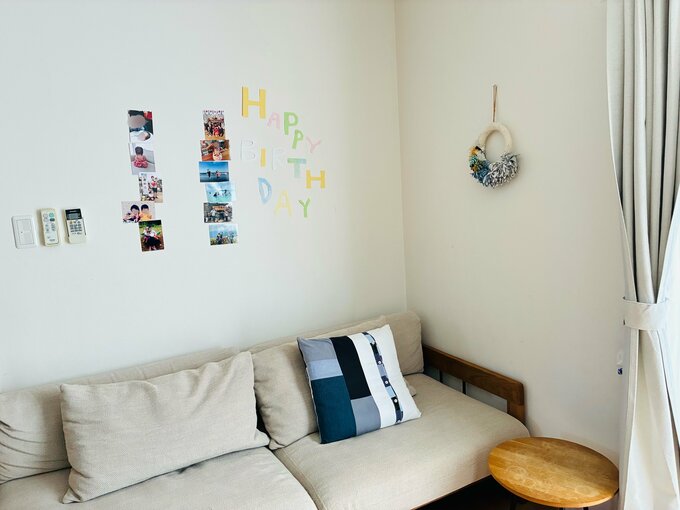 リビングのソファと壁。壁には「HAPPY BIRTHDAY」の文字が切り抜かれた紙と、子どもや家族の思いで写真が飾られている。