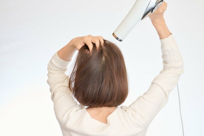 つむじを乾かす女性