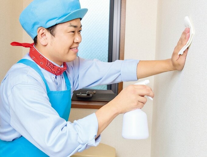 スプレーボトルに入った洗剤をトイレの壁に吹きかけている様子