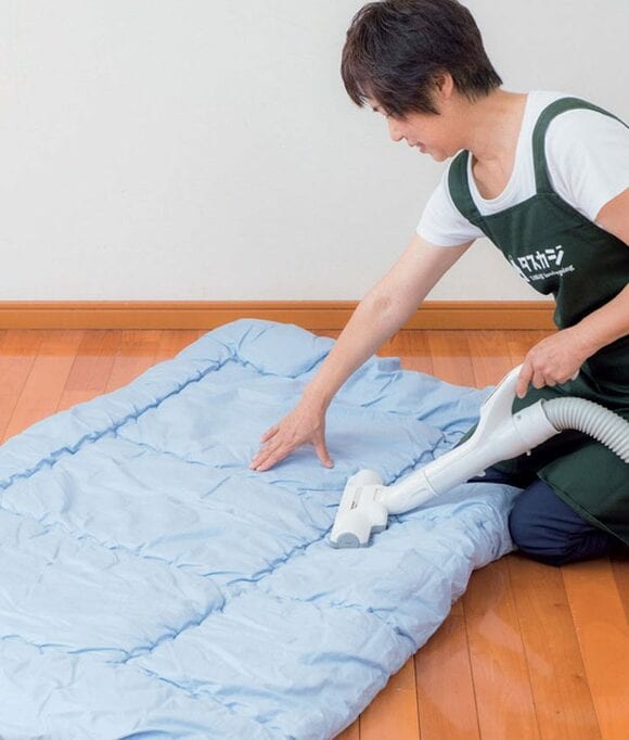 女性お布団に掃除機をかける