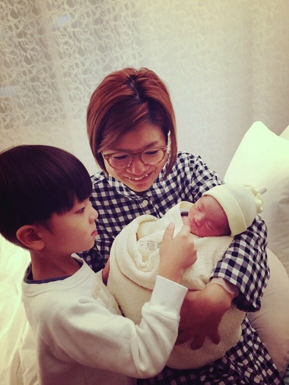 赤ちゃんを抱く女性とみる子ども