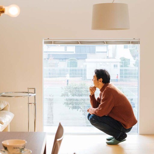 LDKにある大きな窓の向こうを見る田中さん