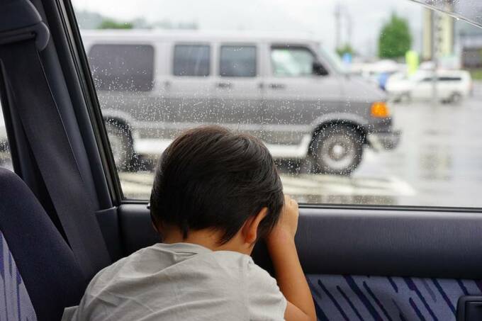 子どもが車の窓にもたれかかっている様子