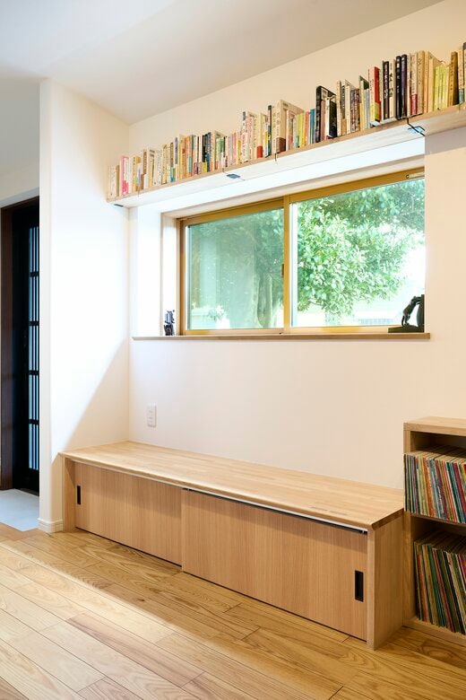 光と風景を取り込む窓の下につくられた、並んで座れる収納つきベンチ 