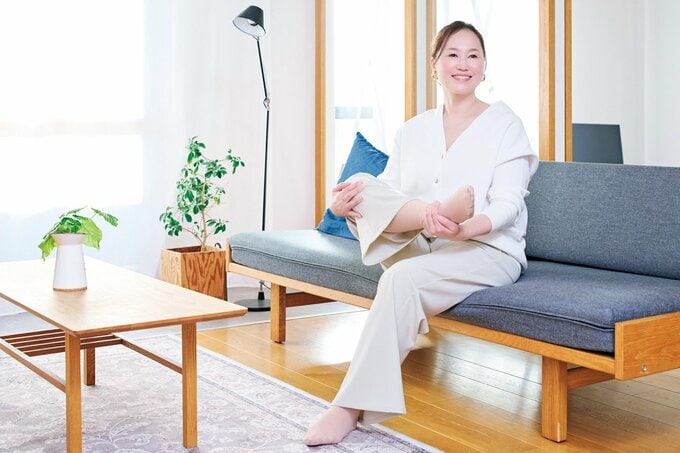 ソファに座り笑顔で脚のストレッチをする女性