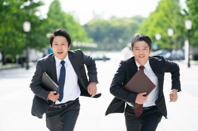 走るスーツの男性2人