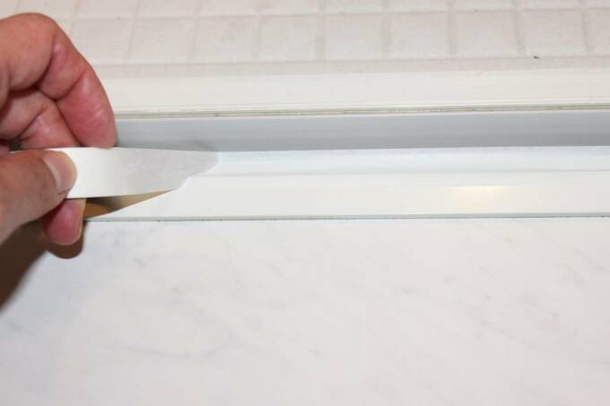 お風呂の扉周りにテープをはる様子