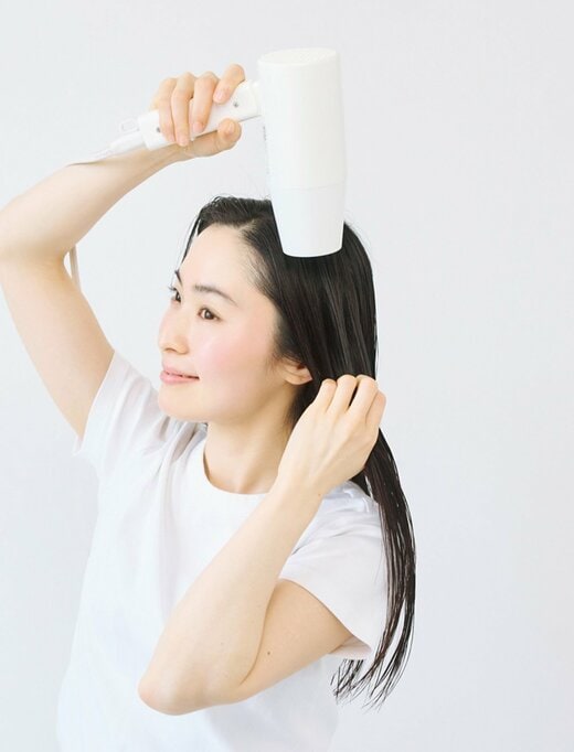 ドライヤーで髪を乾かす女性