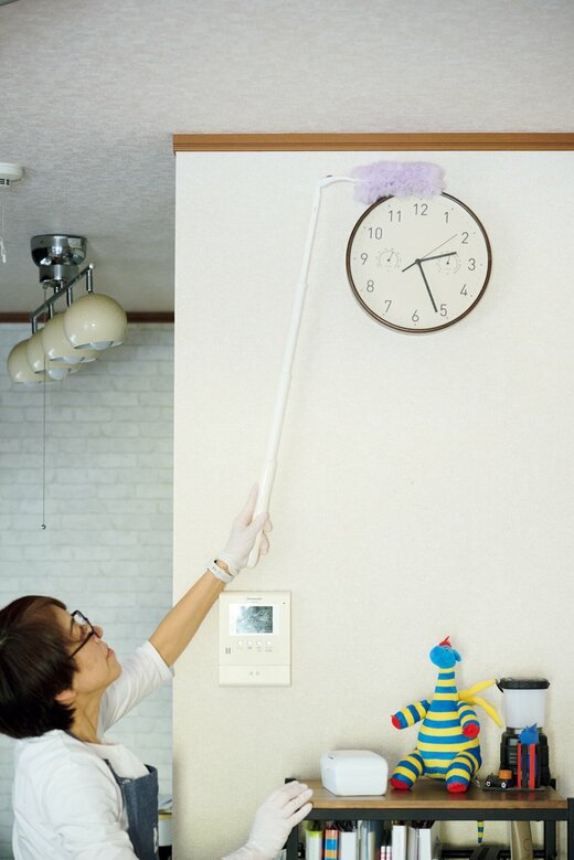 ハンディワイパーで時計の上のホコリを取るハウスキーパー