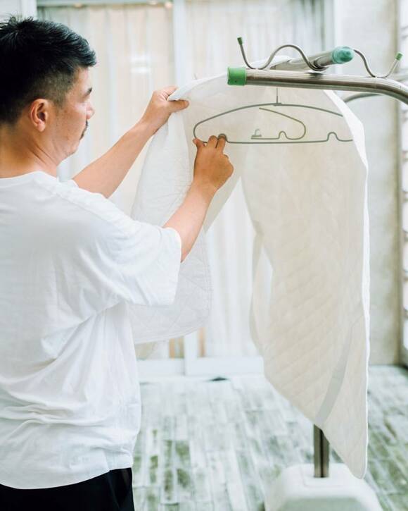 竿にベッドパッドを干す男性