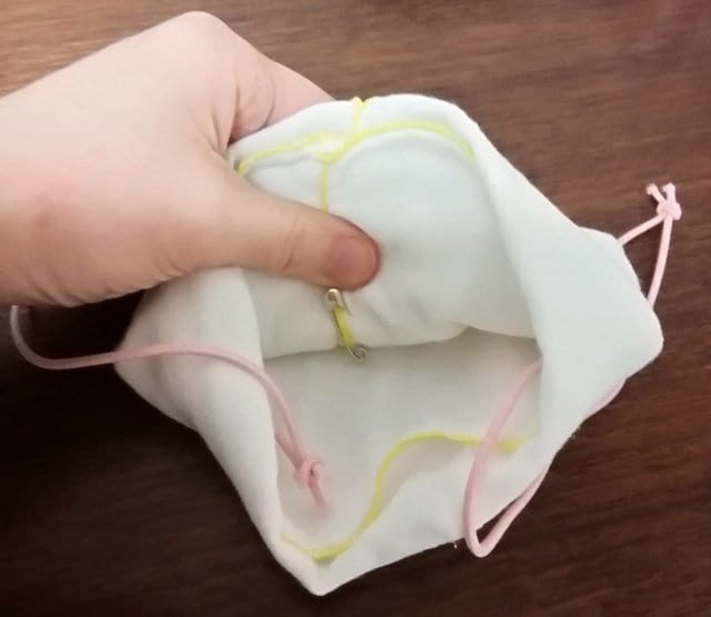 真ん中を1cmくらい重ね、内側から安全ピンで留める様子