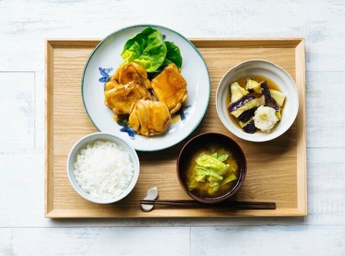 1食分の献立例。左上から時計回りに、鶏の照り焼き、ナスの揚げびたし、キャベツのみそ汁、解凍した冷凍ごはん。しょうゆ味しっかりの照り焼きに、しょうゆ薄めの揚げびたしを組み合わせて