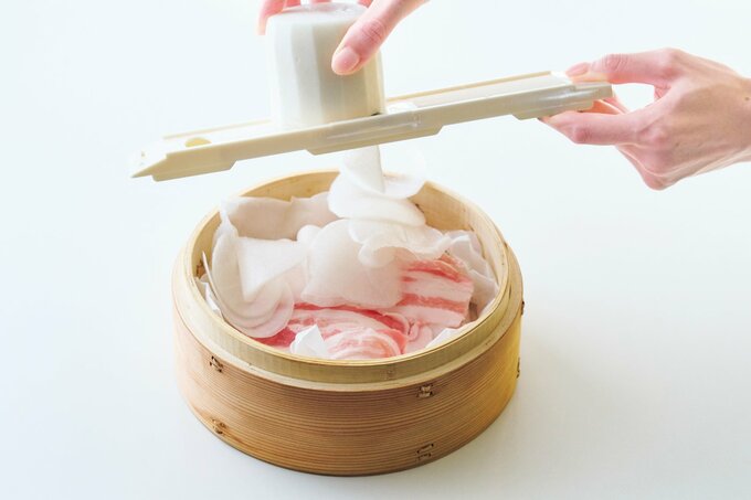せいろに入った豚肉の上に、スライサーで大根をスライスしてのせていく様子