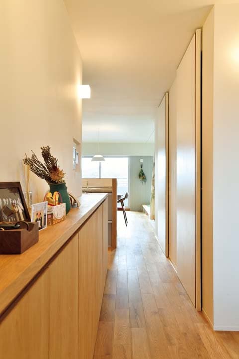 奥行の浅いカウンター収納を造り付けた廊下