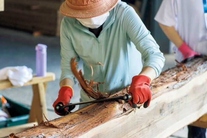 丸太の樹皮をはぐ