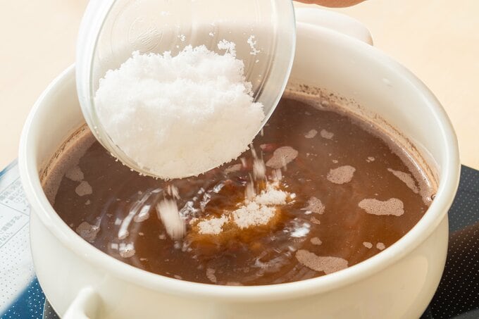 鍋に小豆を戻し、水1リットルを加えて中火にかける。沸騰したらアクを取り、蓋をして弱火で50分〜1時間煮る。小豆が指で軽くつぶれるくらいまで煮えたら火を止め、蓋をして10〜15分蒸らす。再び火をつけ、砂糖、塩を加えて弱火で5〜6分煮る。