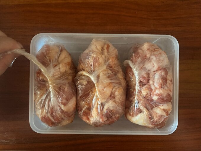 保存容器の中にセットした肉入りのポリ袋の口をひねっている