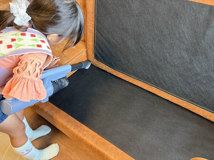 5歳の女の子が掃除機でソファを掃除する様子