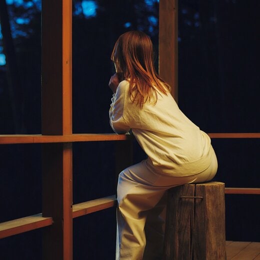 ウッドデッキで夜空を眺める女性の後ろ姿