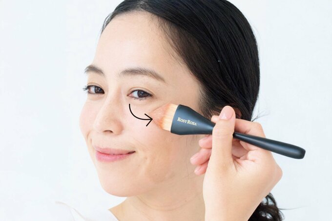 メイクブラシでファンデーションを広げる女性