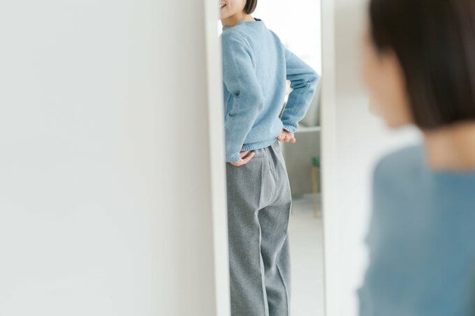 鏡で後ろ姿を見る女性