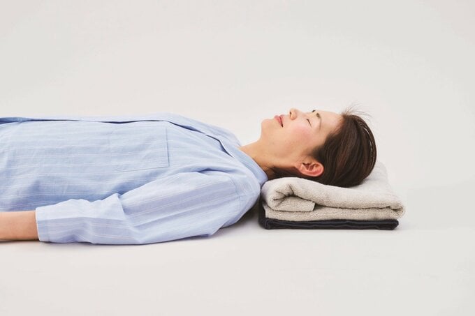 頭の下にバスタオルを敷いて横たわる女性