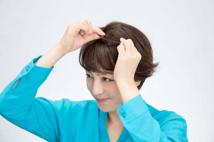 トップの髪をつまむ女性