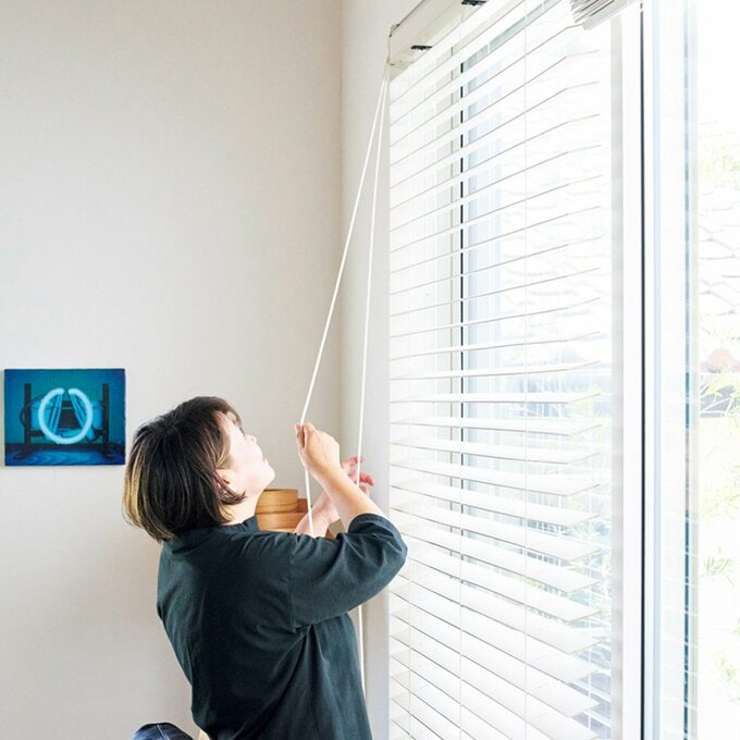 ブラインドカーテンを操作する女性