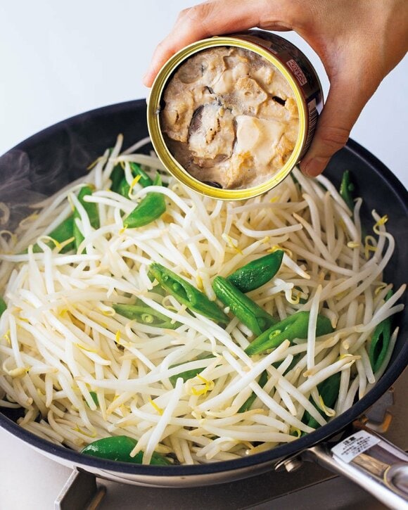 フライパンのモヤシにサバ缶を投入する様子