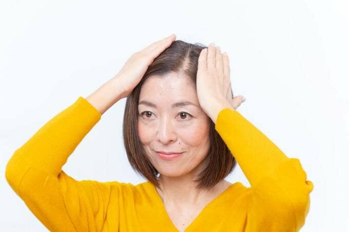 髪を両手でおさえる女性