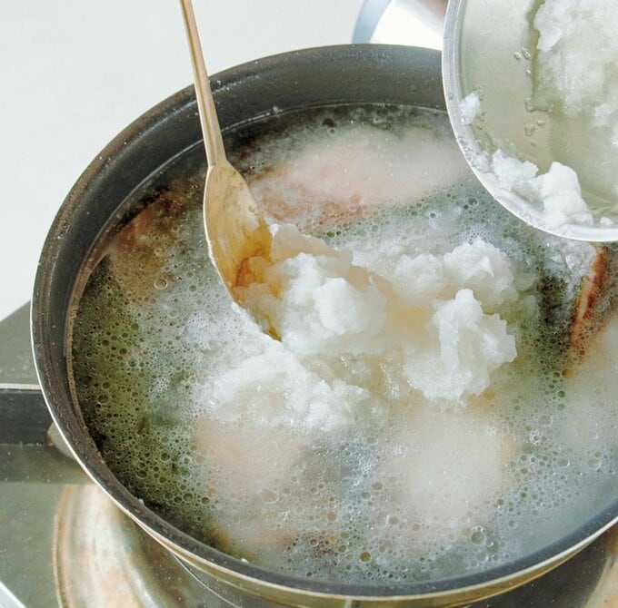 焼いたブリが入った鍋に汁ごと大根おろしを入れる様子