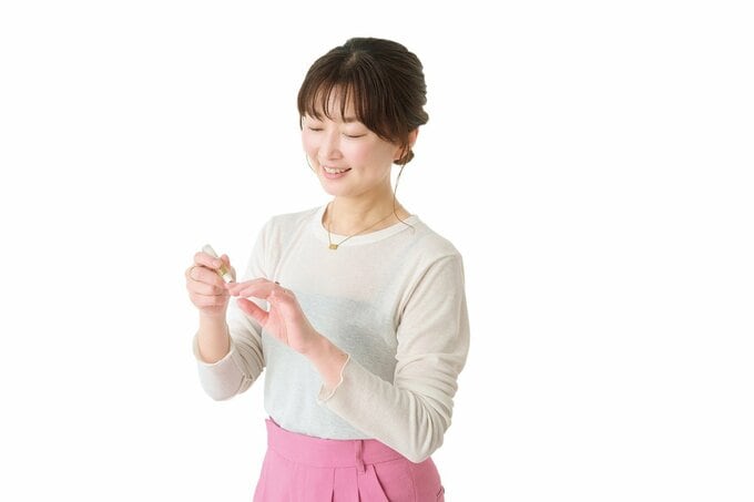 爪にネイルオイルを塗る女性