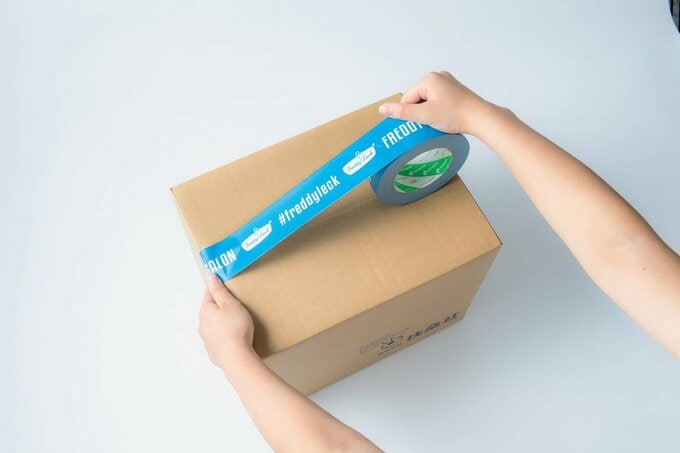 ダンボールにクラフトテープを貼る様子
