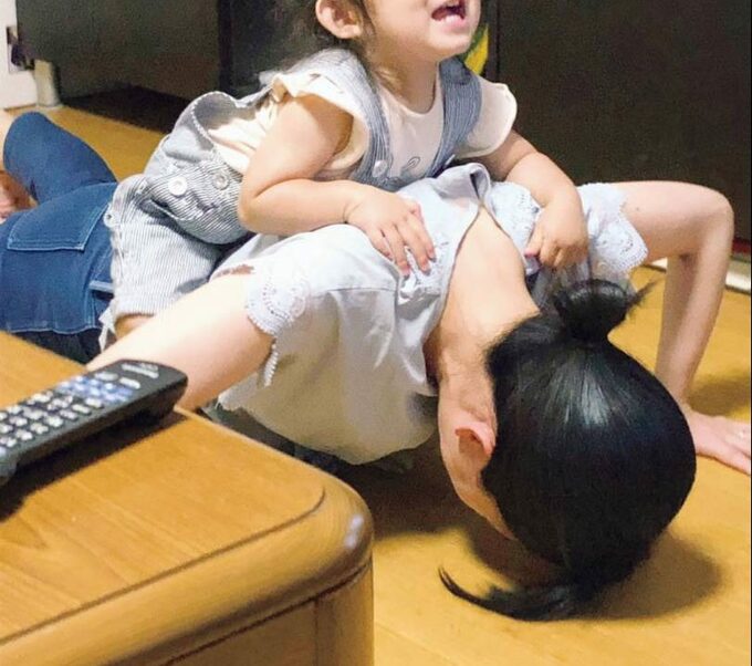 子どもをのせて腕立てをする女性