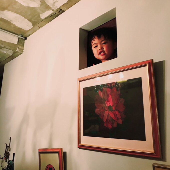 ロフトのくり抜き小窓からのぞく子ども