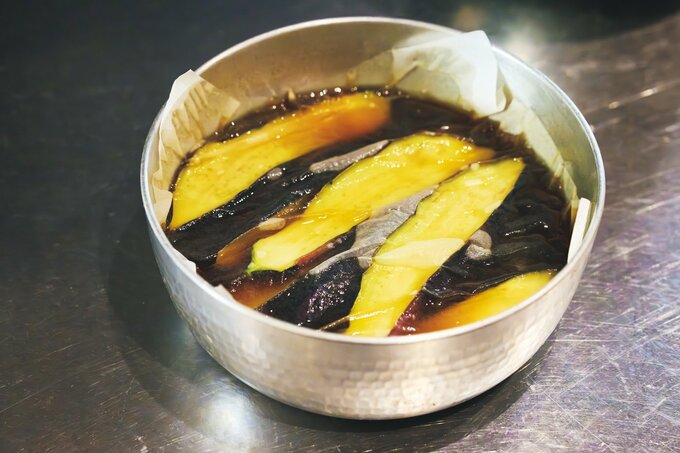 揚げたナスを出汁に浸けている様子