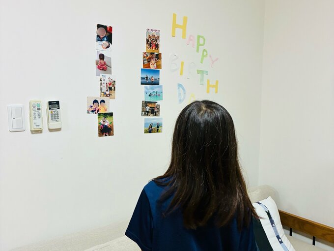 髪の長い人、おそらく子どもの後ろ姿。飾り付けられた壁を見上げている。