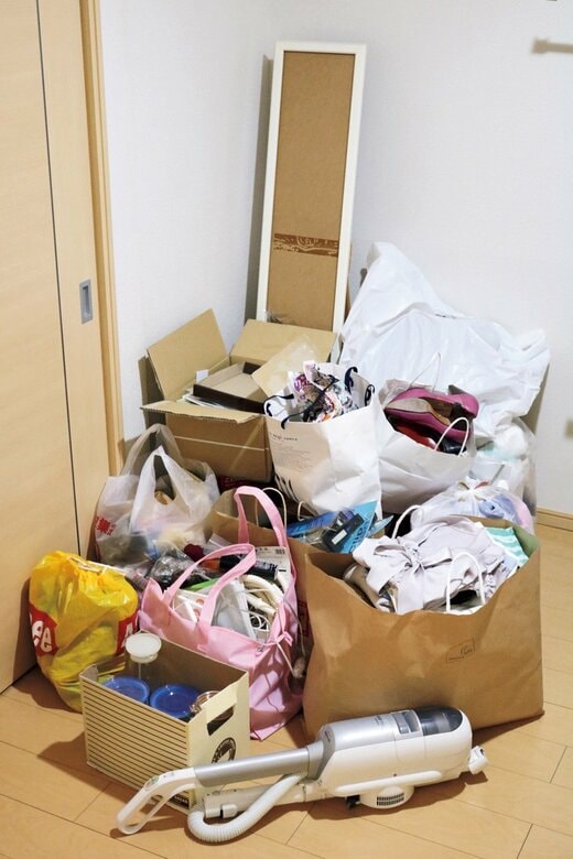 袋や箱に入った服や物であふれた部屋の一角