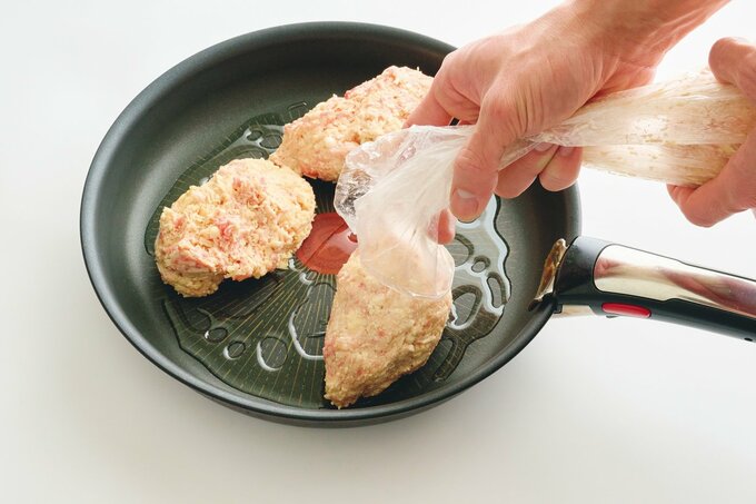 ビニール袋からフライパンへ肉ダネを絞り出す様子