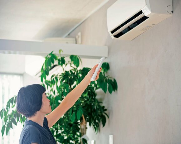 女性エアコンのリモコンを利用中