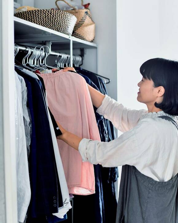 クローゼットのハンガーにかけられた衣類を持つ女性