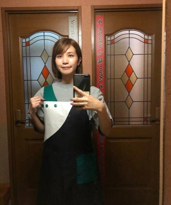 扉の前にスマホを持つ女性