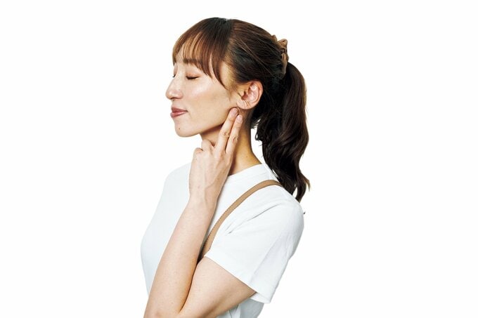 耳の下あたりを指で押さえる女性